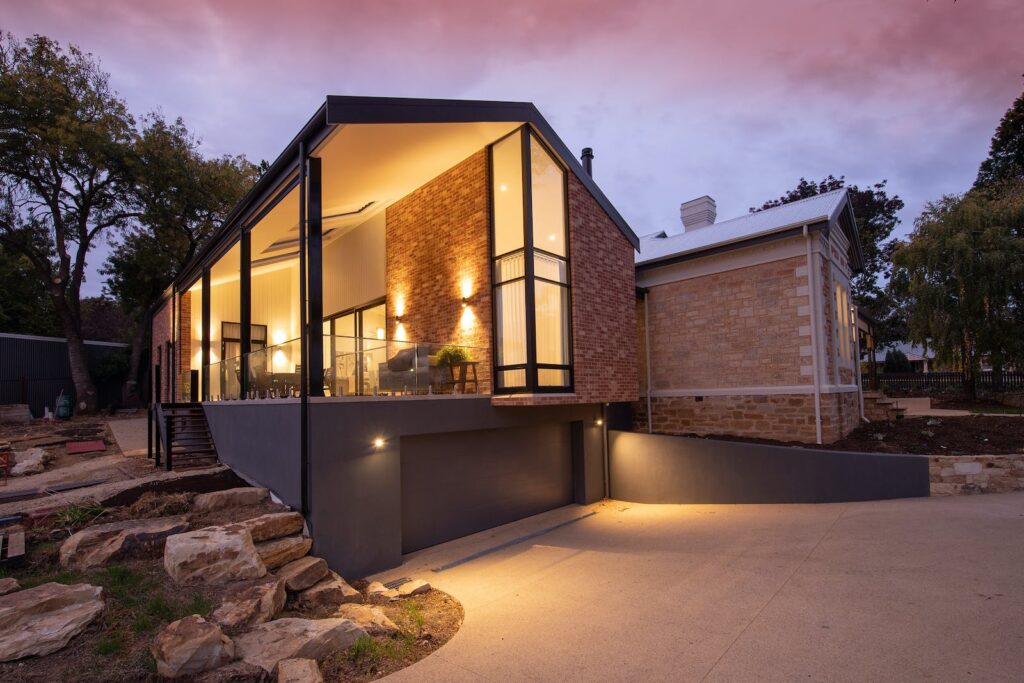 Contemporary building facade with glowing lamps near walkway at sunset